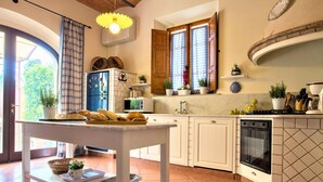 A kitchen with white cabinets, a built-in oven, a sink, and a window with curtains. - Lavish Villa in Peccioli (Peccioli)