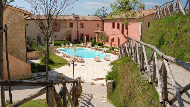 A pool area with lounge chairs and a wooden fence.