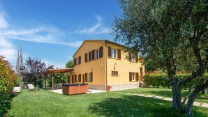 Ein zweistöckiges Haus mit einer überdachten Terrasse und einem Whirlpool im Garten.