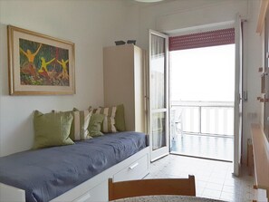 Una stanza con un letto, un quadro, un armadio e una vista attraverso una porta.