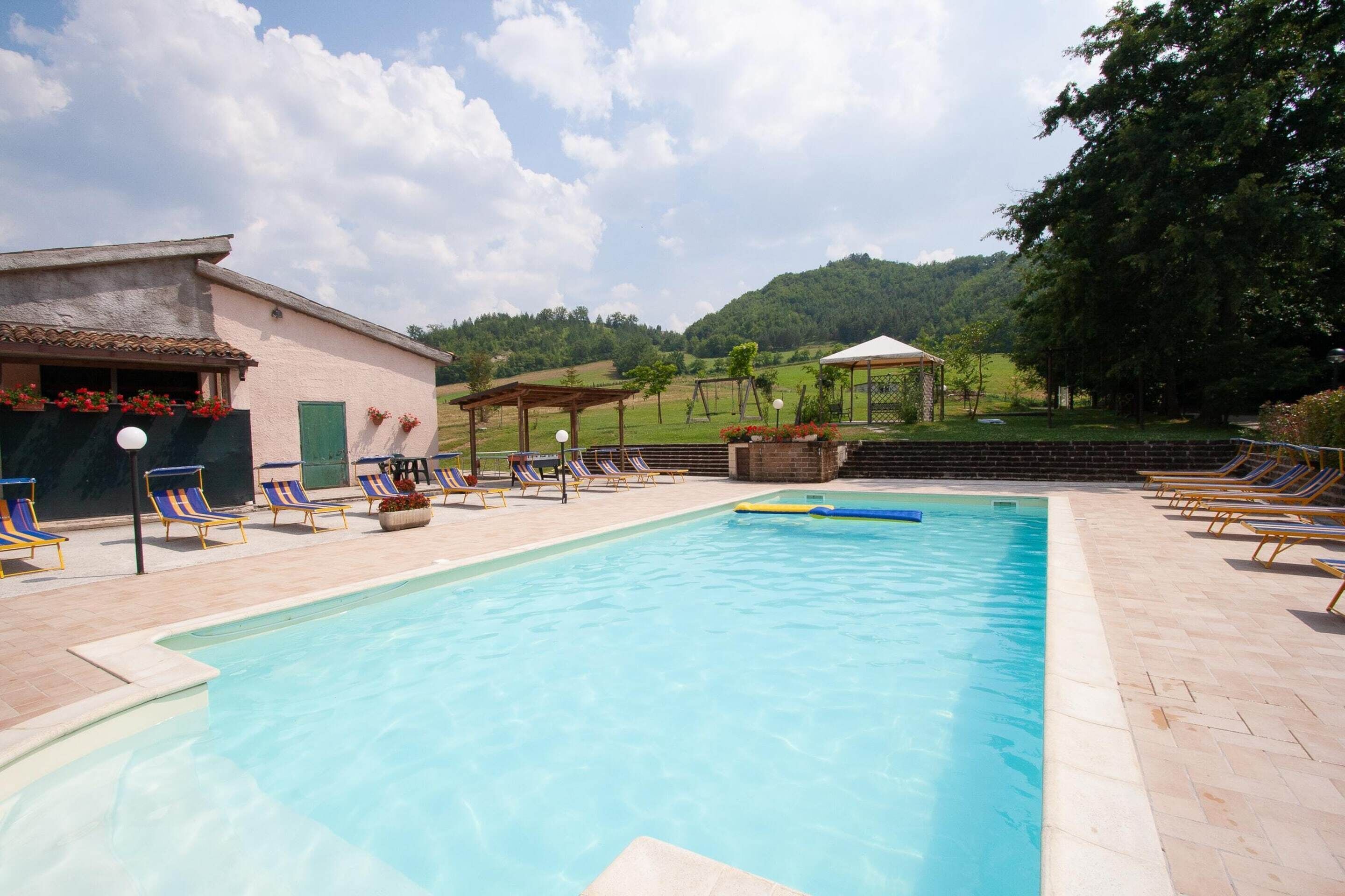 A swimming pool with lounge chairs and a gazebo in a landscaped area.