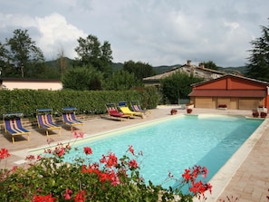 A pool area with lounge chairs and a clear pool.