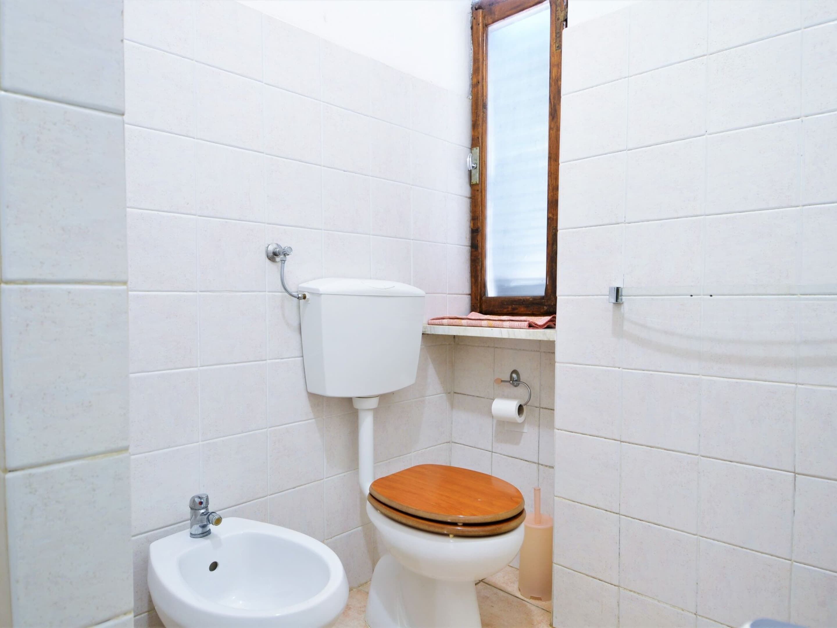 Un baño pequeño con inodoro, bidé y un espejo sobre el lavamanos.