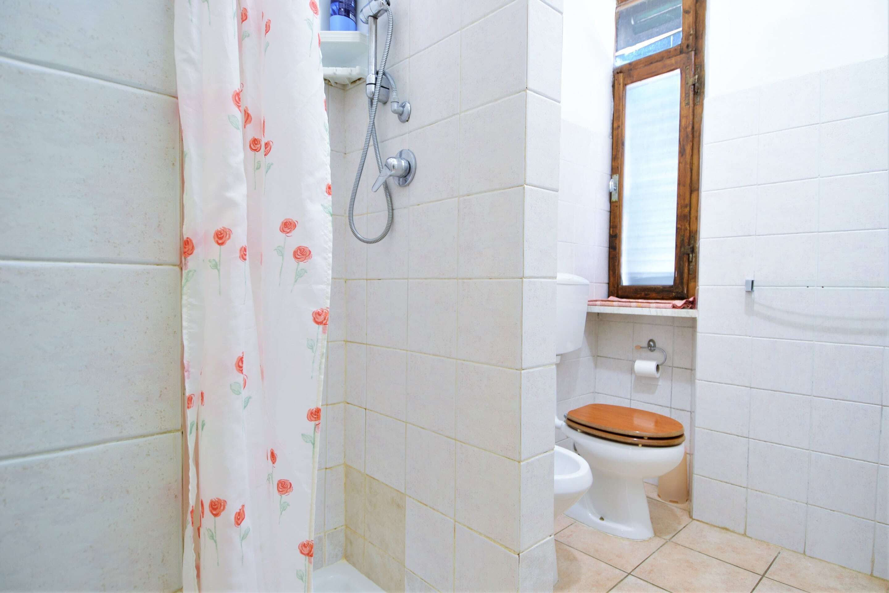 Une salle de bain avec une douche, des toilettes et une fenêtre.