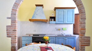 A kitchen with blue cabinets, a stove, and a sink. There is a table with chairs and a vase of flowers. - Apartment in Massa Marittima With Pool (Massa Marittima)