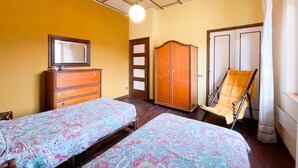A room with two beds, a wardrobe, a chair, and a mirror. - Belvilla by OYO Grappolo D'uva (Esanatoglia)