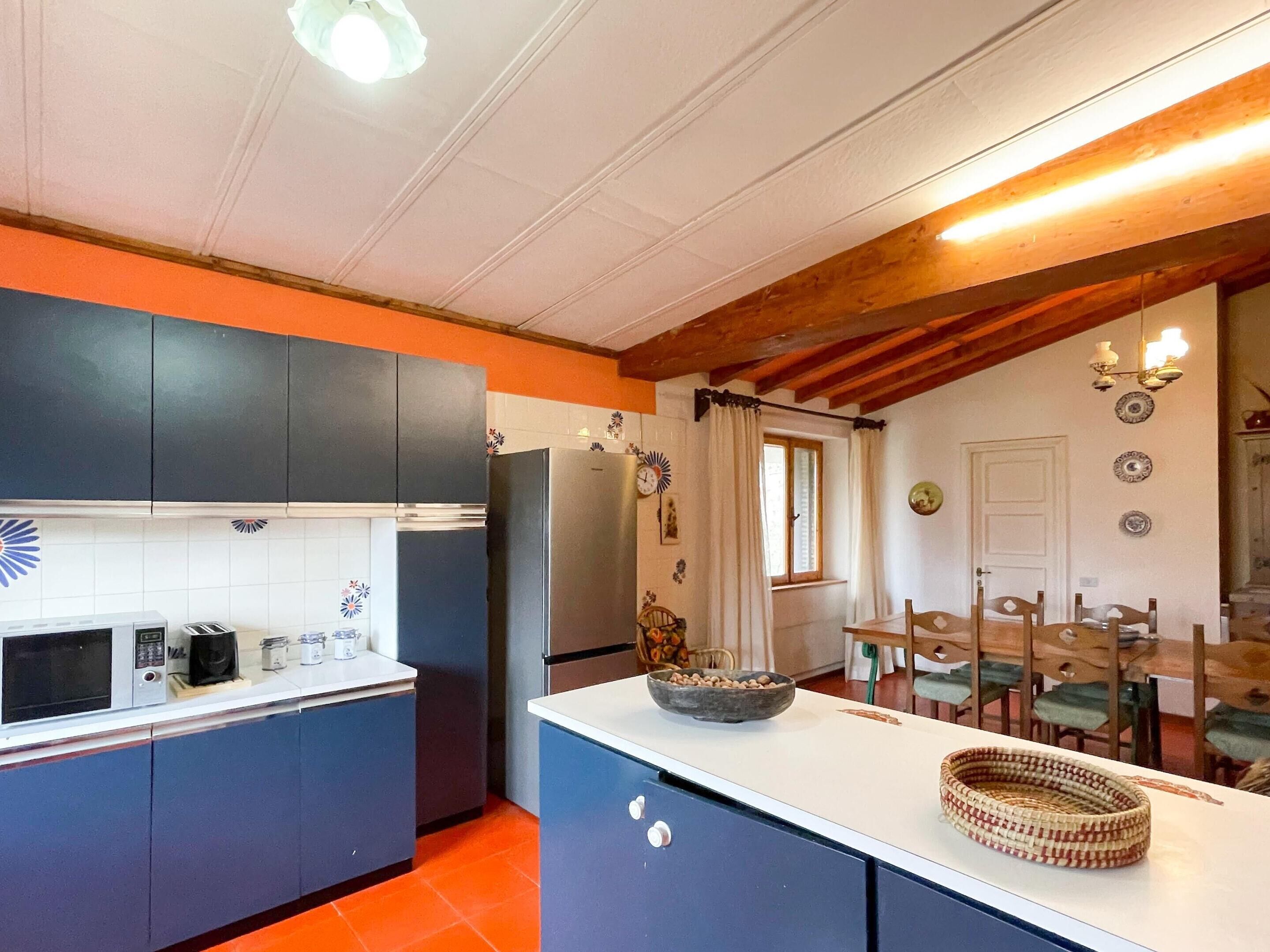 A compact kitchen with modern appliances, a dining area with wooden furniture, and a visible window.
