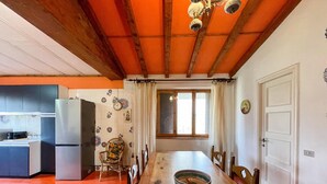 A dining area with a wooden table, chairs, and a large window. - Belvilla by OYO Grappolo D'uva (Esanatoglia)