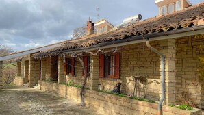 A traditional brick building with a tiled roof, a covered porch, and a small garden area. - Belvilla by OYO Grappolo D'uva (Esanatoglia)