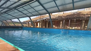 A swimming pool with a covered area, surrounded by brick buildings and a metal roof structure. - Belvilla by OYO Grappolo D'uva (Esanatoglia)