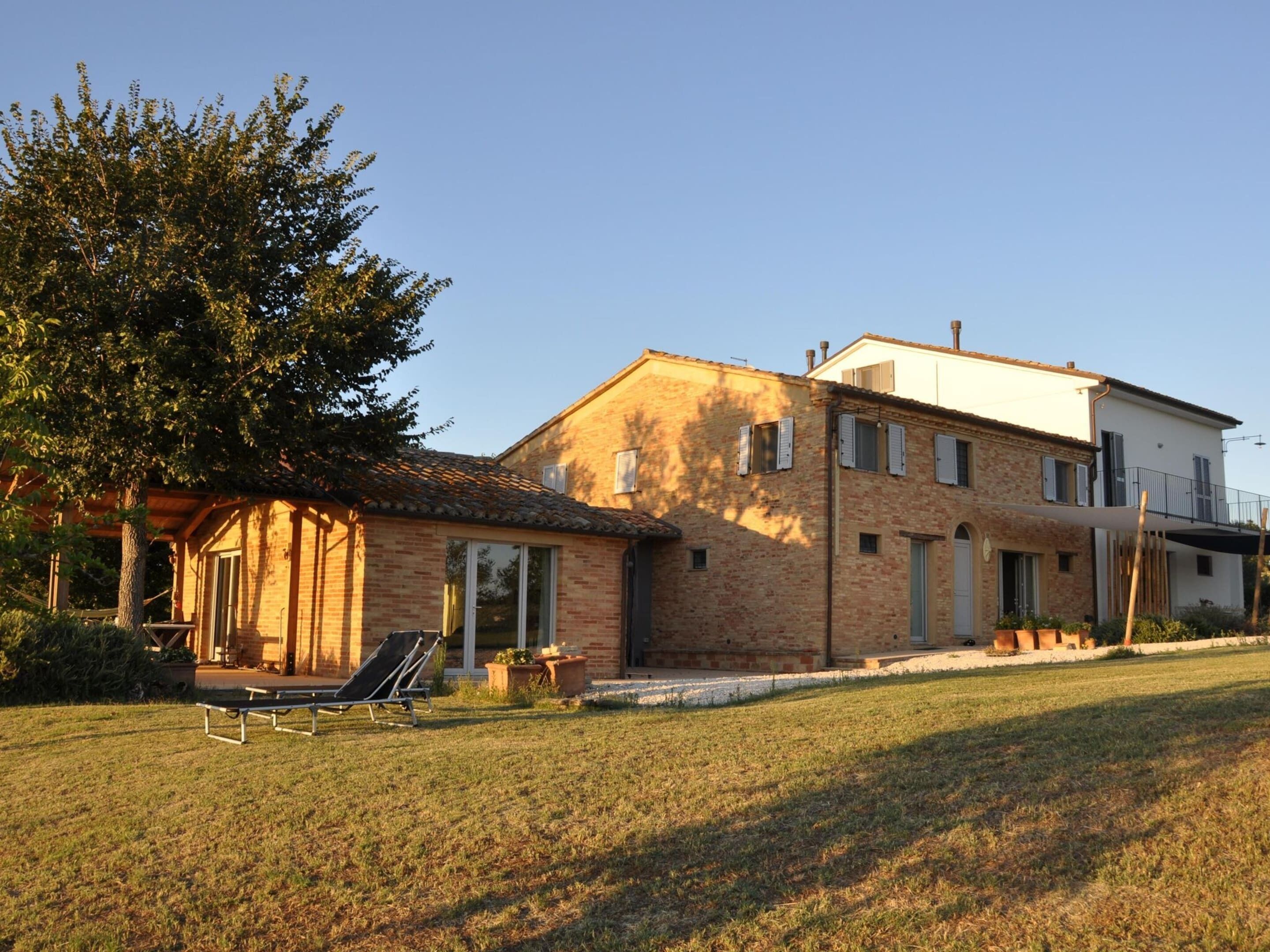 Une maison à deux étages avec une façade en briques, un balcon et une pelouse.