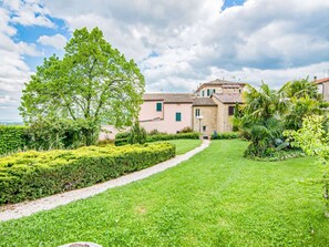 A well-maintained garden with a gravel path leading to a stone building with a tiled roof.