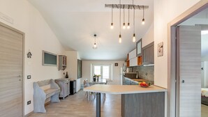 A modern kitchen with a central island, pendant lighting, and a dining area with a bench and table. - Country Escape in Matelica (Matelica)
