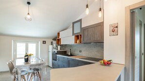 A modern kitchen with a central island, wooden cabinets, and pendant lighting. - Country Escape in Matelica (Matelica)