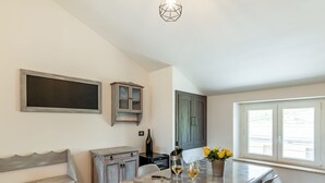 A dining area with a table set for two, a bench, a cabinet, and a window with blinds. - Country Escape in Matelica (Matelica)