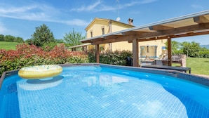 A swimming pool with a wooden deck and a house in the background. - Country Escape in Matelica (Matelica)