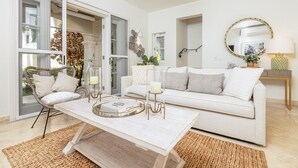 Ein modernes Wohnzimmer mit einem weißen Sofa, einem Couchtisch mit Dekoration und einem Korbstuhl.