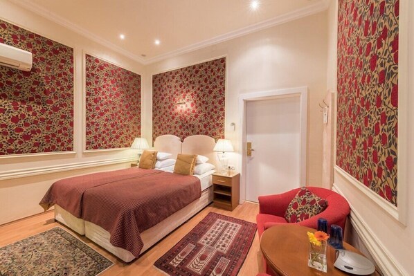 A hotel room with a large bed, two bedside tables, a chair, and a small table with a vase of flowers.