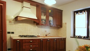 Una cocina con gabinetes de madera, cocina a gas y ventana con cortinas.