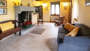 A cozy living room with a fireplace, a sofa, a chair, and a television. - Belvilla by OYO Rossini (Urbania)