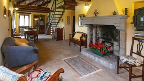 A spacious living area with a fireplace, wooden beams, a staircase, and a dining area. - Belvilla by OYO Rossini (Urbania)