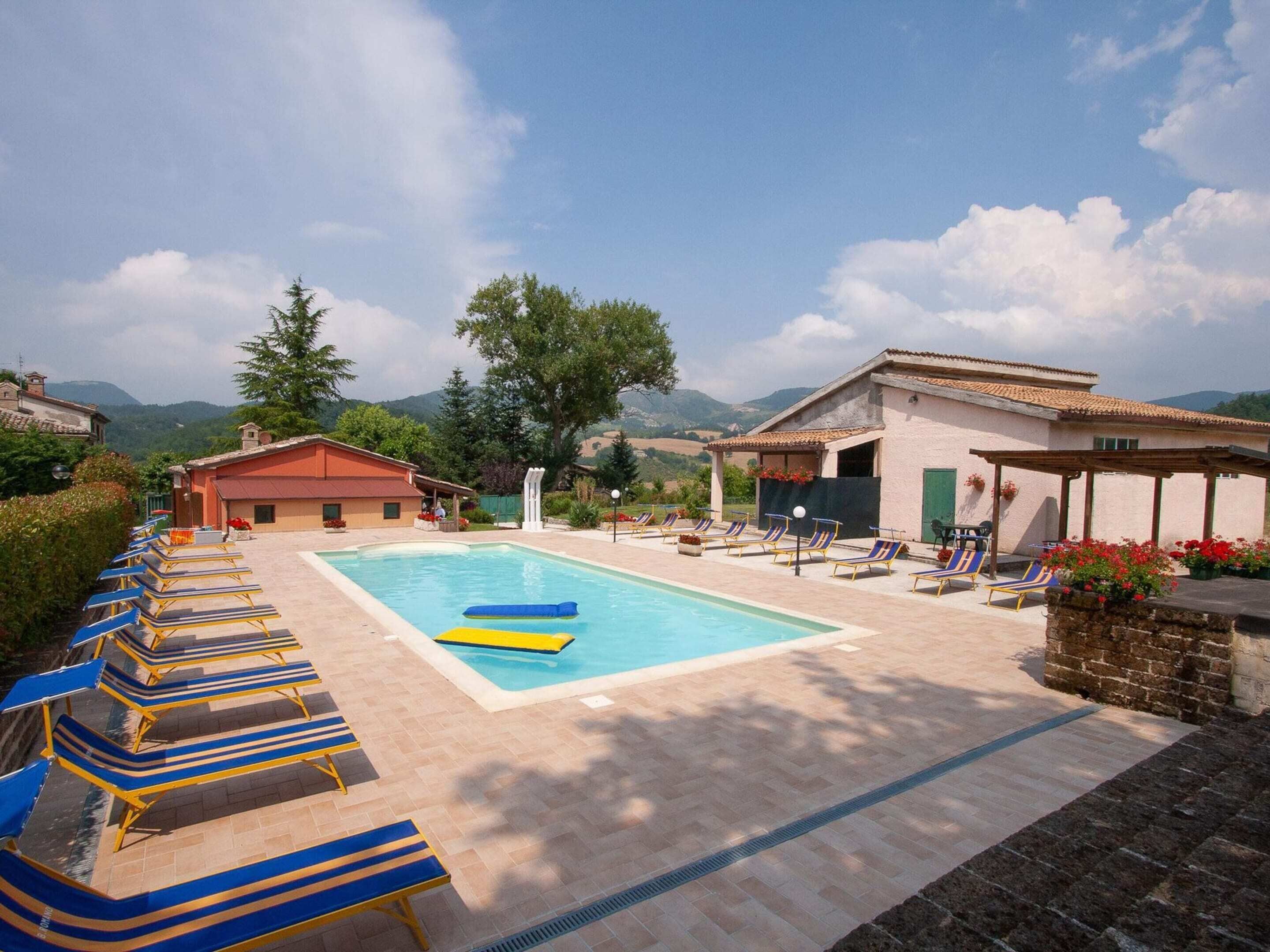 A pool area with lounge chairs, a pool, and a view of the mountains.