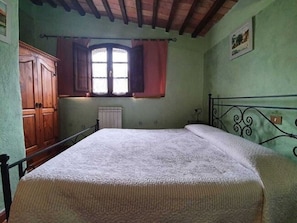 A bedroom with a bed, wooden wardrobe, and a window with shutters. - Tranquility at Bellavista (Seggiano)