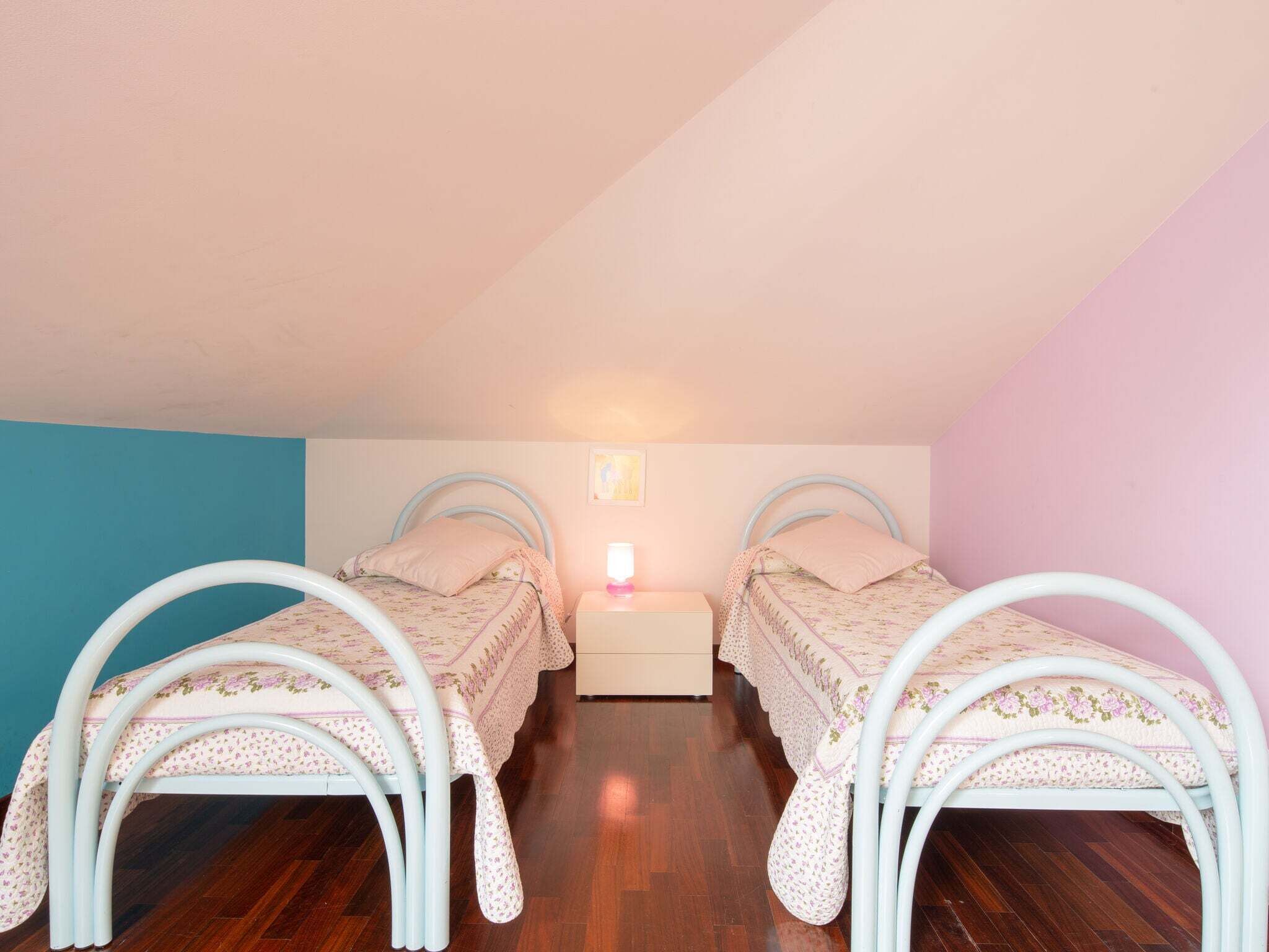 Ein Schlafzimmer mit zwei Einzelbetten, einem Nachttisch und einer Wandleuchte.