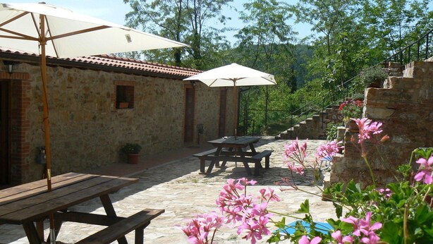 A stone building with a tiled roof, outdoor seating, and a staircase leading up. - Massa Marittima Residence With Pools (Massa Marittima)