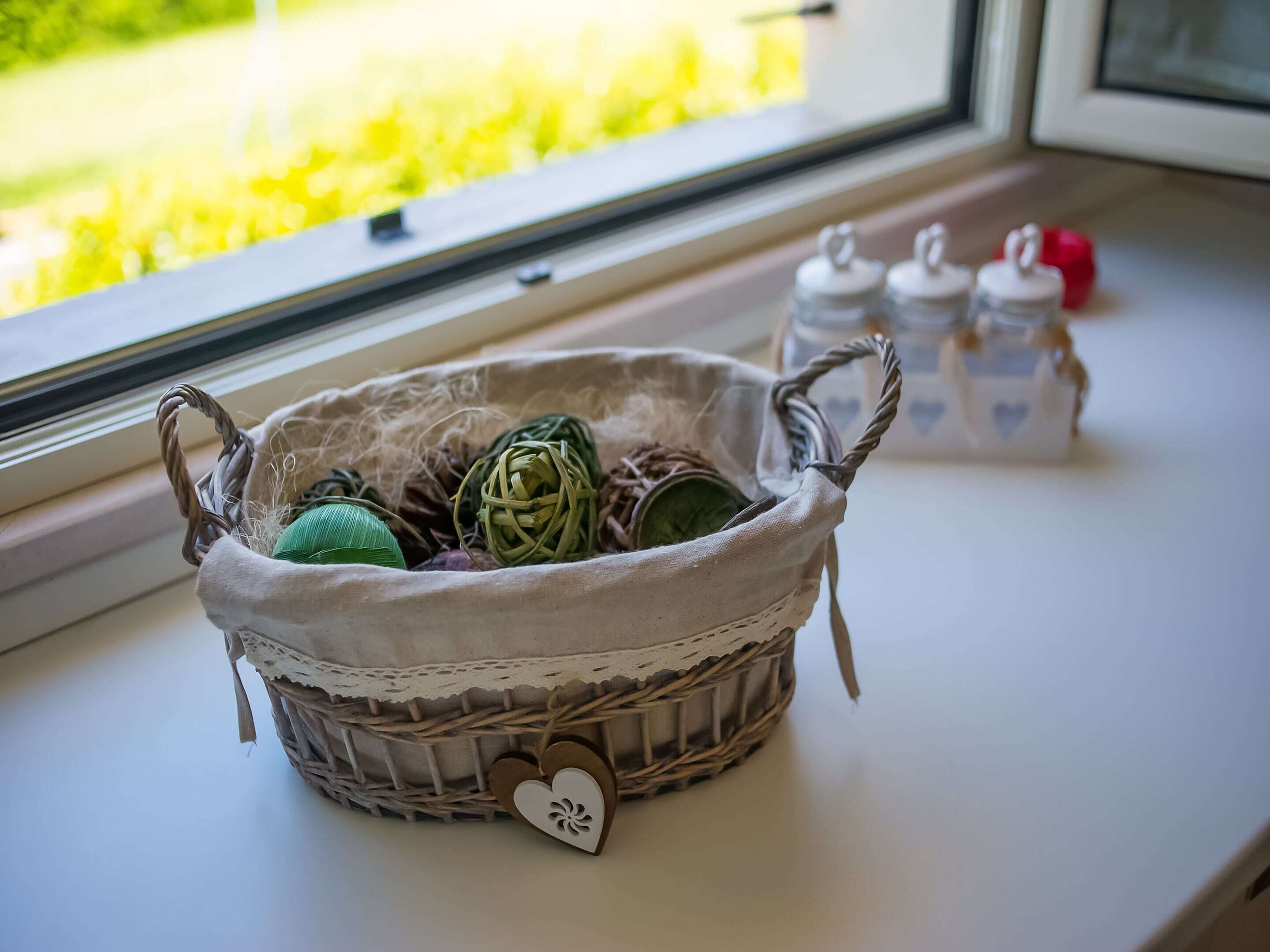 A wicker basket with a heart-shaped tag on a windowsill.