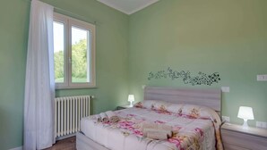 A bedroom with a bed, two bedside tables, a radiator, a window with curtains, and a wall decoration. - Villa in Borgo Pace With Private Pool (Borgo Pace)