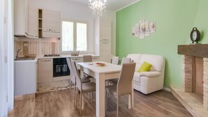 A modern kitchen with white cabinets, a dining table with chairs, a white sofa, and a green accent wall. - Villa in Borgo Pace With Private Pool (Borgo Pace)