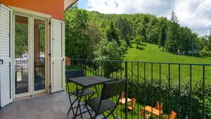 A balcony with a table and chairs, overlooking a green landscape with trees and a hill. - Villa in Borgo Pace With Private Pool (Borgo Pace)