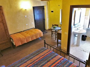 A room with a bed, a table with chairs, a sink, and a door.
