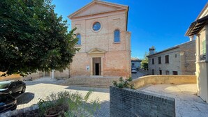A small brick building with a central door and windows, surrounded by a cobblestone courtyard and potted plants. - Pleasant Holiday Home With Whirlpool (Colli al Metauro)