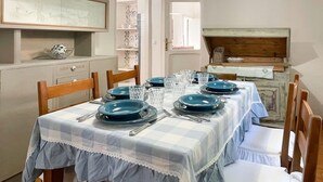 A dining area with a table set for six, featuring blue plates and clear glasses. - Pleasant Holiday Home With Whirlpool (Colli al Metauro)