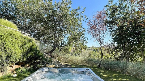 A hot tub in a garden with a stone staircase leading up to it, surrounded by trees and greenery. - Pleasant Holiday Home With Whirlpool (Colli al Metauro)