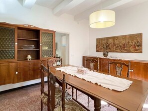 Uma sala de jantar com uma mesa de madeira, cadeiras, um candelabro e um quadro na parede.