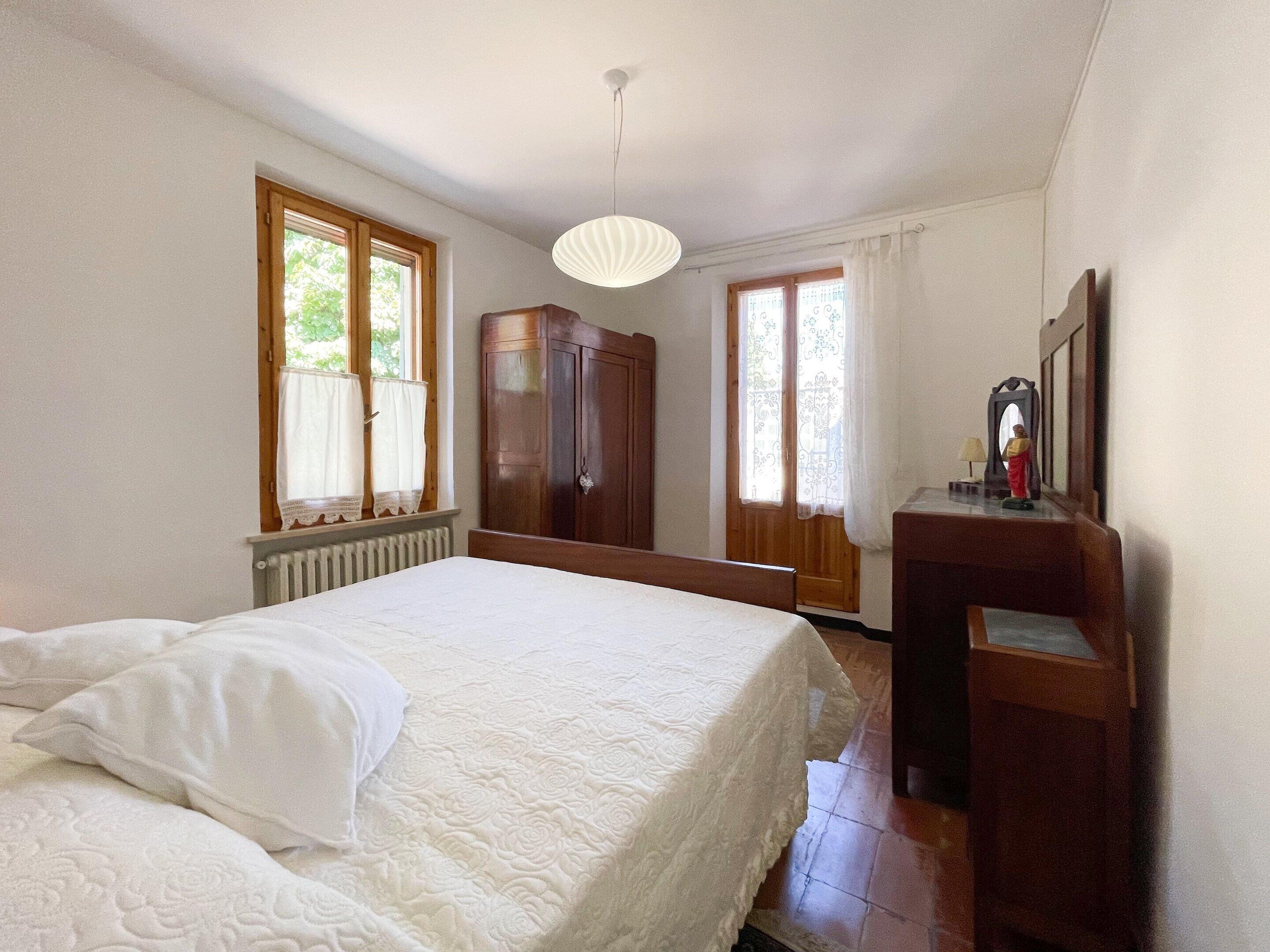 A bedroom with a bed, a wardrobe, a desk, and a mirror.