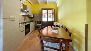 A compact kitchen with a dining area, featuring a wooden table and chairs, a stove, and a sink.