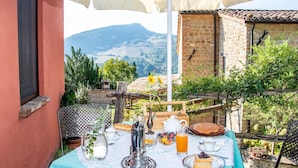 Une table dressée à l’extérieur, avec vue sur des montagnes, un bâtiment en briques et une clôture en bois.