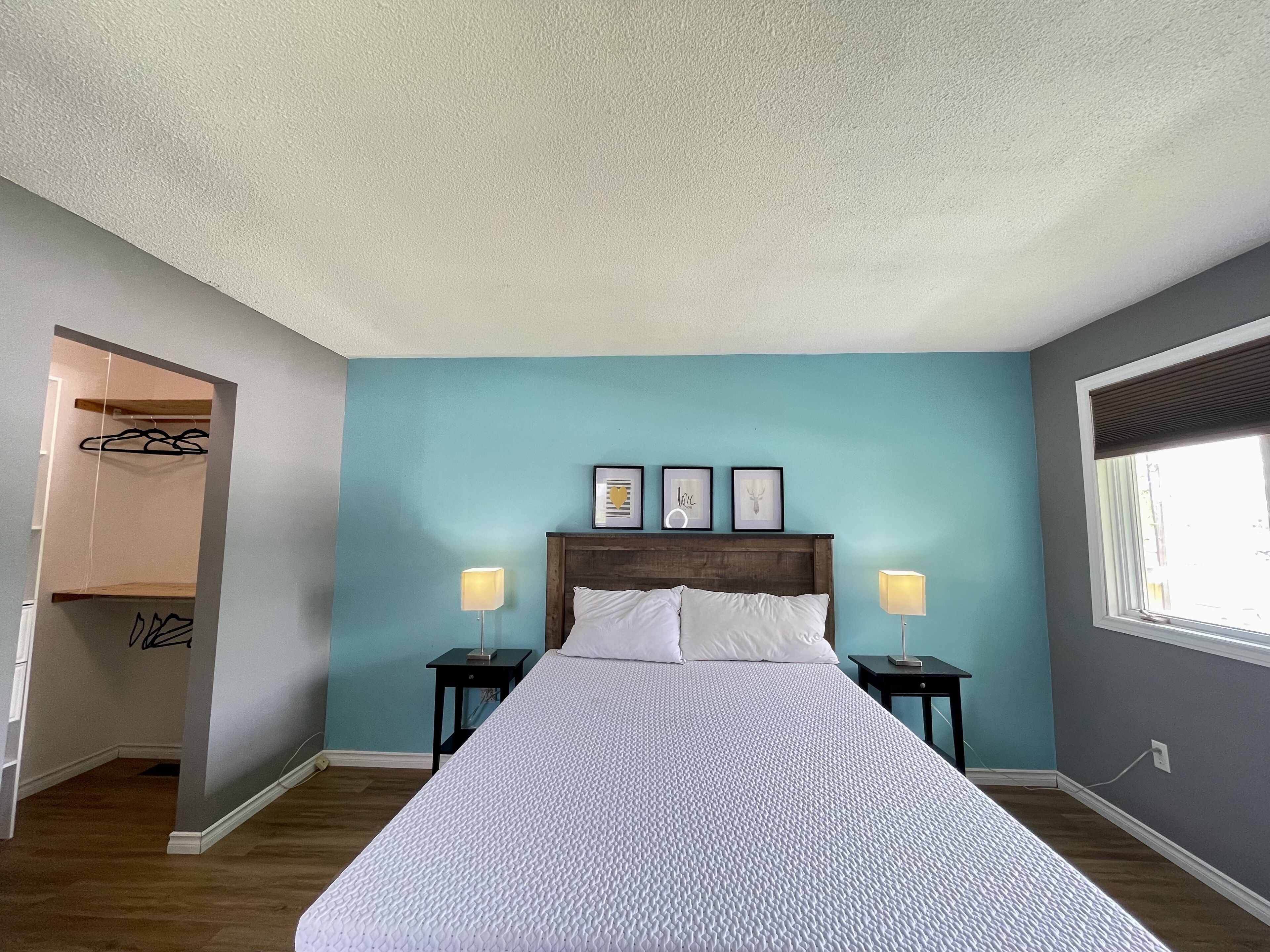 A bedroom with a bed, two bedside tables, a nightstand, a window, and a door leading to a closet.