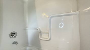 A white bathtub with a built-in seat and grab bars.