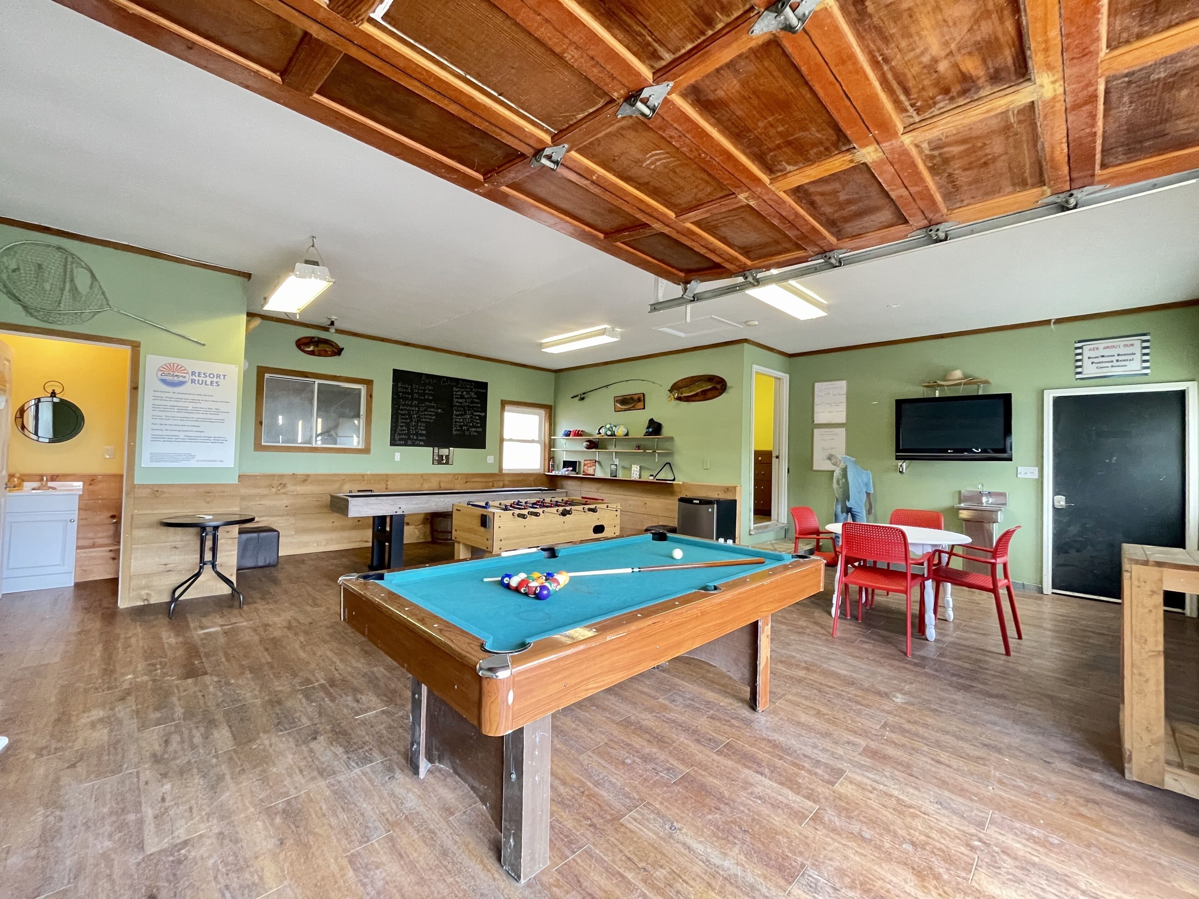 A pool table in a room with wooden floors and a high ceiling.