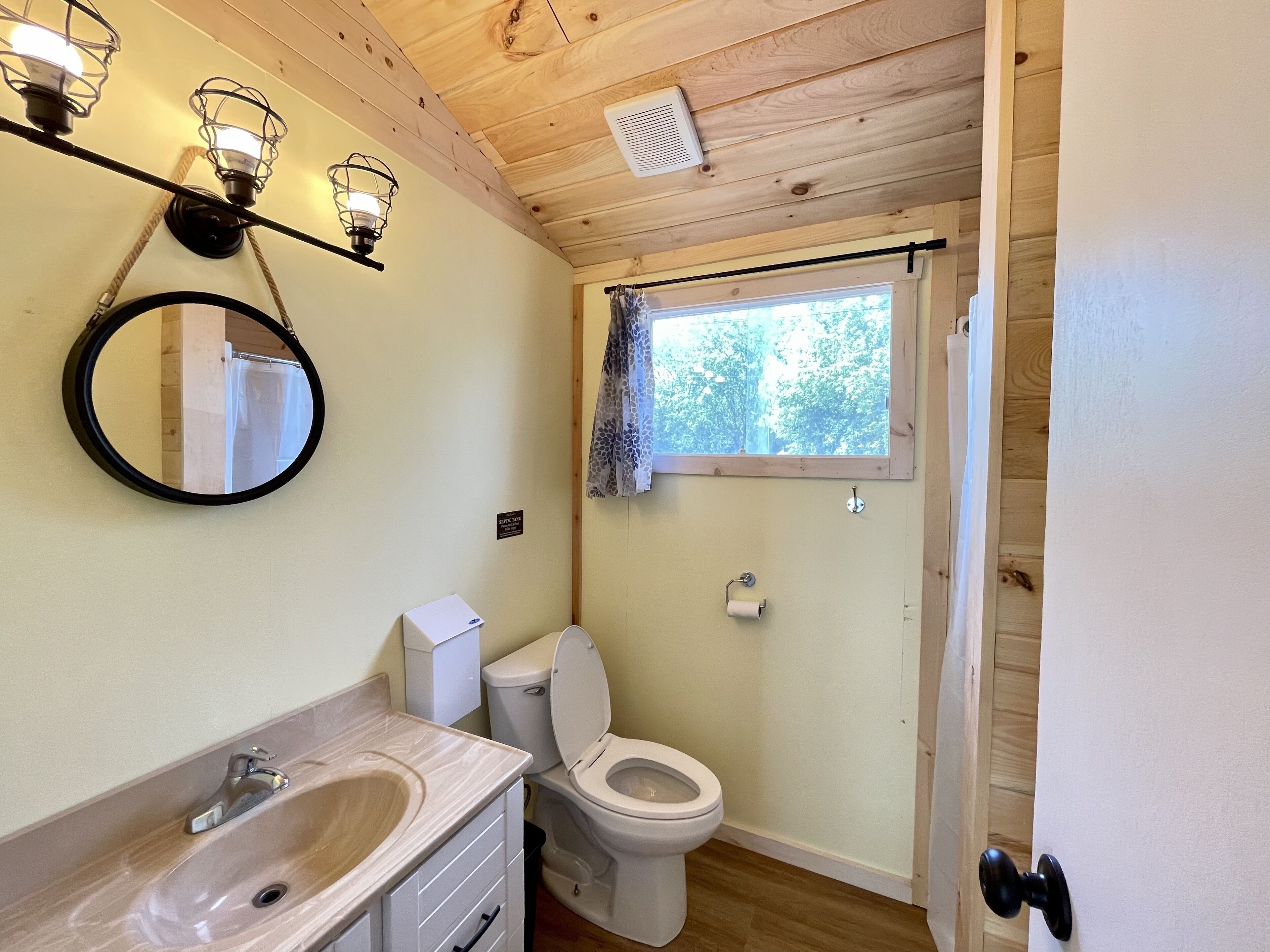 A bathroom with a toilet, sink, and a mirror.
