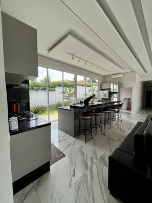 Una cocina moderna con una isla central, taburetes de bar y un ventanal con vistas a un jardín.
