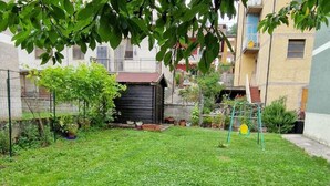 A residential backyard with a small play area, including a swing set and a slide. - Belvilla by OYO Appartamento a Tagliacozzo (Tagliacozzo)
