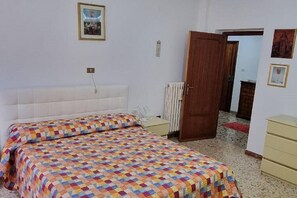 A bedroom with a bed, a nightstand, a wooden door, and a radiator. - Belvilla by OYO Appartamento a Tagliacozzo (Tagliacozzo)