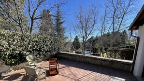 A patio with tiled flooring, a metal chair, a wooden table, and a metal fence enclosing a swimming pool. - Chalet in Monte Sibillini Park (Amandola)