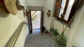 A narrow hallway with a stone floor, a wooden door leading outside, and a window with a view of the outside. - Chalet in Monte Sibillini Park (Amandola)
